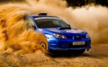 Синий Subaru Impreza поднимает столб пыли на песке